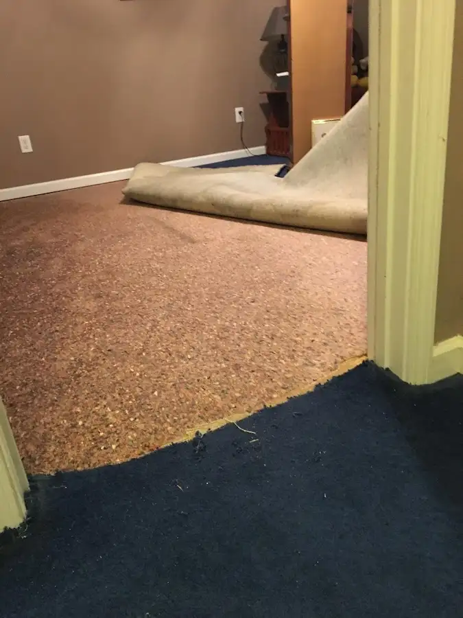 Carpet pad removal revealing water damage during Water Mitigation Services in Smithtown